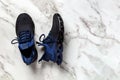Laced up grooved men shoes on a marble floor. Pair of black blue mesh fabric sneakers for fitness and active lifestyle. New