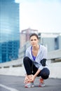 Laced up and ready for the streets. Portrait of a young female jogger tying up her shoes before a run through the city. Royalty Free Stock Photo