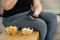 Fat woman watching series at tv eating junk food