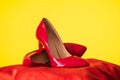 Lacquered shiny women`s red stilettos on a yellow background