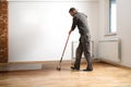 Lacquering wood floors. Worker uses a roller to coating floors