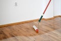 Lacquering wood floors. Worker uses a roller to coating floors Royalty Free Stock Photo