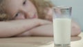 Lactose-intolerant child sadly looking at glass of fresh white milk, nutrition