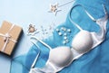 Lacy bra on a blue fabric, next to pearl stars, a wooden herringbone and a gift box. Royalty Free Stock Photo