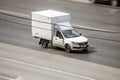 Lada Granta van moving on a street. White small pickup motor car rushes on the road with blurred road background. Aerial front