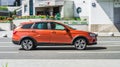 Lada Vesta SW Cross rides on a street. Orange 5-door station wagon motor car rushes on the road with blurred background