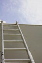 Ladder against gray color wall, blue sky background Royalty Free Stock Photo