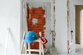 Ladder, blue protective helmet and ear defenders at construction site. Home improvement. Bricks wall Royalty Free Stock Photo