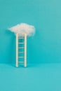 Ladder with a cloud on top, blue colored background, copy space, dreaming of success, creative and business concept, achieving