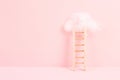 Ladder with a cloud on top, pink rose colored background, copy space, dreaming of success, creative and business concept