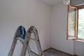 Ladder, roller and paint roller, buckets with paint in an empty room ready to get paint. Painting walls, reconstruction works Royalty Free Stock Photo