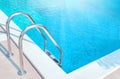 Ladder stainless handrails stairs into the swimming pool with blue water and sunlight blik of sun. Vacation, relax, healthy. Royalty Free Stock Photo