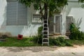Ladder standing in the green garden. Gardening concept. Trimming overgrown branches from a tree in a residential Royalty Free Stock Photo