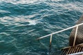 Ladder to the water on the beach. Rusty stairs for descending into the blue sea on a concrete pier. Plastic trash in the Royalty Free Stock Photo