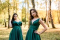 Ladies in elegant green dresses walking in autumn park. Brunette girl Dreamy young girls laughing on the outdoors