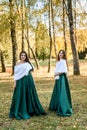 Ladies in elegant green dresses walking in autumn park. Brunette girl Dreamy young girls laughing on the outdoors