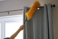 Cleaning the window and curtains area with a fluffy yellow duster Royalty Free Stock Photo