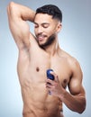 The ladies love a man that smells good. a young man applying deodorant against a studio background.