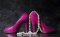 Ladies pink high heels with long strand of white pears against a Royalty Free Stock Photo