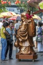 Ladies stop to pray to a Buddha statue in a street in Singapore.