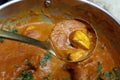 A ladle full of Paneer Butter Masala , a rich and creamy Indian dish made of Paneer or Tofu in tomato and cream gravy