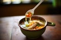 ladle full of soup, showing chicken, rice, and carrots