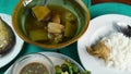 Ladle of a piece of chicken and winter melon from a ceramic bowl and place on a plate of steam rice.