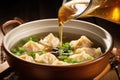 ladling wonton soup into a ceramic bowl Royalty Free Stock Photo