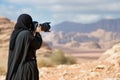 lady in abaya photographing desert landscape