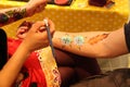 A lady artist painting on young`s man hand