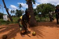 A lady bending with a big knife in front of a coconut