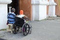 Lady, Blind Man beside disabled Beggar in wheelchair at Church yard Gate Portal