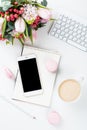 Lady bloggers work desk with pink flowers and macaron cakes on w