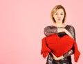 Lady with blond hair puts her arms around toy heart. Royalty Free Stock Photo