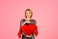 Lady with blond hair puts her arms around toy heart. Royalty Free Stock Photo