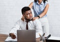 Lady boss sexually molesting her attractive male subordinate, putting hands on his shoulders at company office Royalty Free Stock Photo