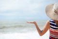 Lady in broadbrim hat facing sun standing on sandy