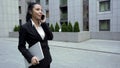 Lady in business suit with laptop having informal chat on phone, end of work day Royalty Free Stock Photo