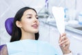 Lady checks her teeth in the mirror. Young woman in the dentists office Royalty Free Stock Photo