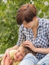 Lady with child playing outdoor. Beautiful boy put head on mother`s knees.