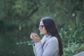 Lady in coat drinking warm tea