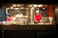 A lady cooking takoyaki at Takoyaki shop at Takoyakushi street in Kyoto. Takoyaki is a ball-shaped