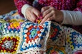 lady crocheting colorful granny squares for a quilt