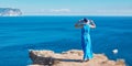 Lady in dress and hat posing on cliff top. Sea view and fresh air. Travel time and journey abroad concept, copy space Royalty Free Stock Photo