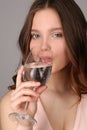 Lady drinking water from a bocal. Close up. Gray background Royalty Free Stock Photo