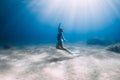 Lady free diver in swimsuit posing underwater at the deep in blue sea with sunlight Royalty Free Stock Photo