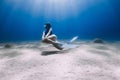 Lady freediver with fins posing and glides underwater in blue sea with sunlight Royalty Free Stock Photo