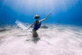 Lady freediver with fins posing and glides underwater in blue sea with sunlight Royalty Free Stock Photo