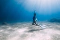 Lady freediver posing underwater at the deep in blue sea with sunlight Royalty Free Stock Photo