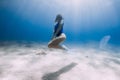 Lady freediver with white fins posing and glides underwater in ocean with sunlight Royalty Free Stock Photo